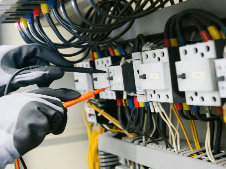 Técnico revisando un tablero eléctrico con un instrumento de medida