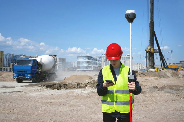 Trabajador con casco y chaleco consultando su teléfono en una obra